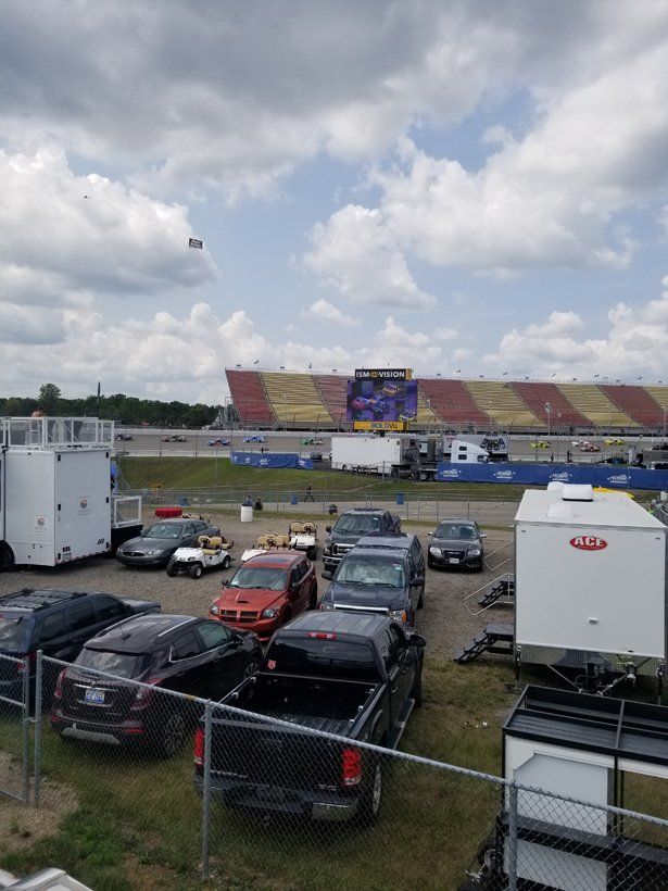 A lot of cars are parked in a parking lot in front of a stadium.