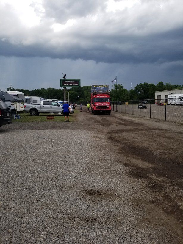 A red truck is parked in a gravel lot under a cloudy sky