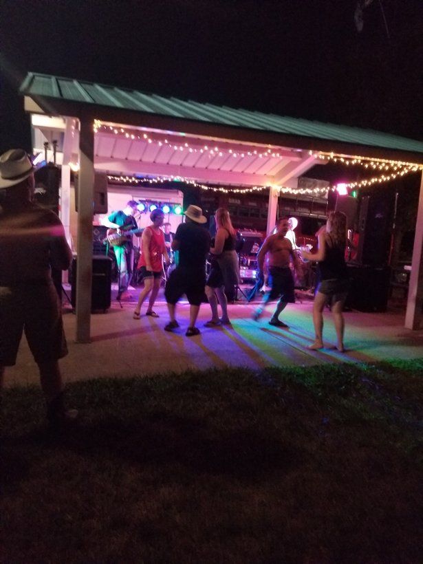 A group of people are dancing under a pavilion at night.