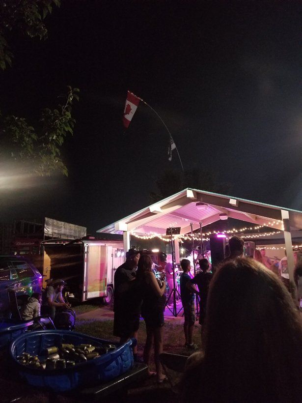 A group of people are standing under a tent at night.
