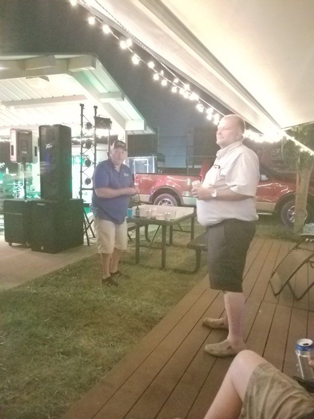 Two men standing on a deck with a red truck in the background