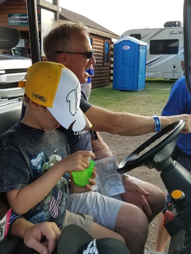 A man and a boy are sitting in a golf cart.