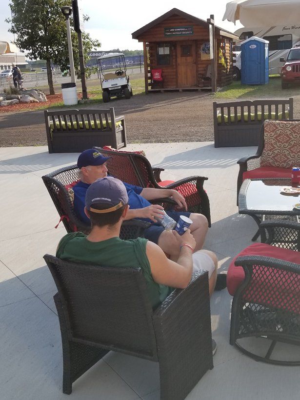 Two men are sitting on a patio with a shed in the background