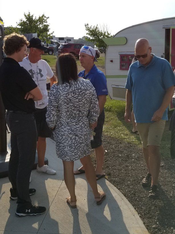 A group of people standing on a sidewalk in front of a trailer