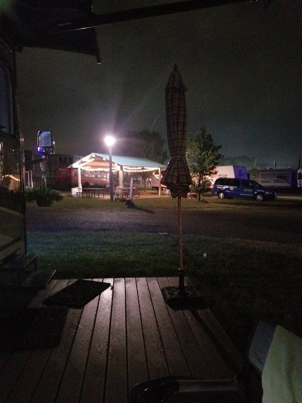 A view of a park at night from a deck with an umbrella in the foreground
