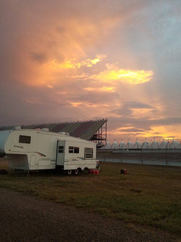 A rv is parked in a field at sunset