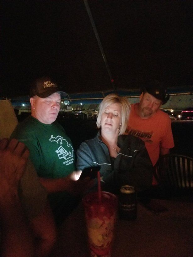 A group of people are sitting at a table looking at a cell phone.