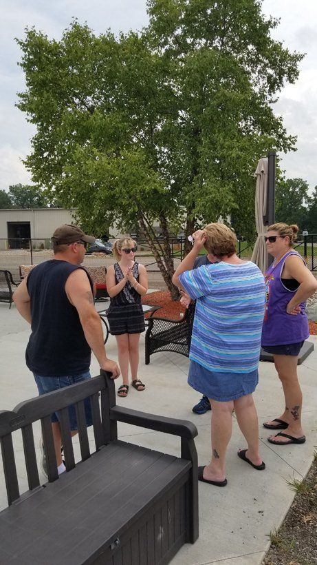 A group of people are standing around a bench in a park.
