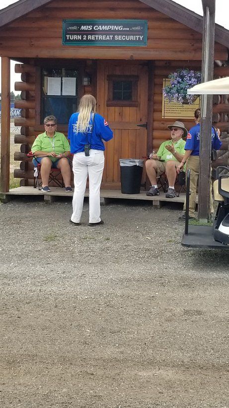 A group of people are sitting outside of a log cabin.