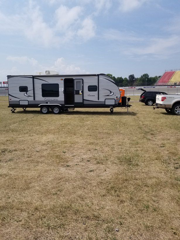A trailer is parked in a grassy field next to a truck.