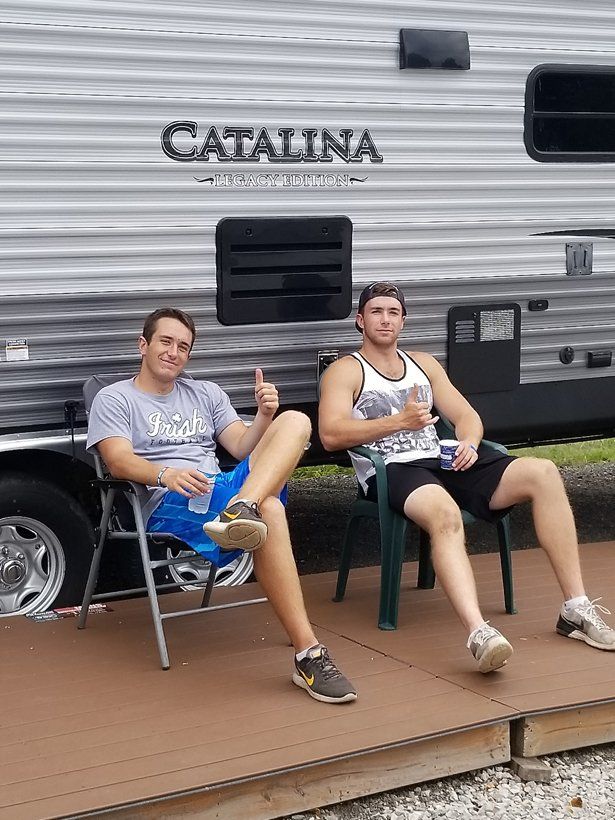Two men are sitting in chairs in front of a trailer.