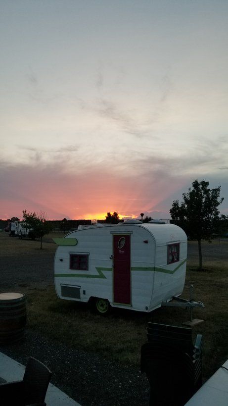 A small trailer is parked in a field at sunset.