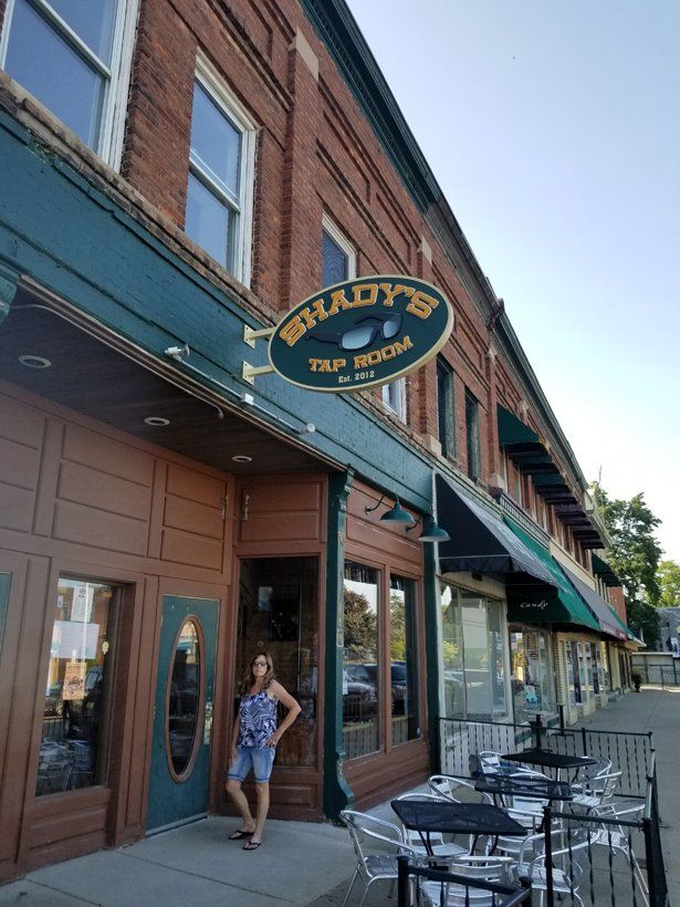 A woman is standing in front of a lady 's pub and restaurant