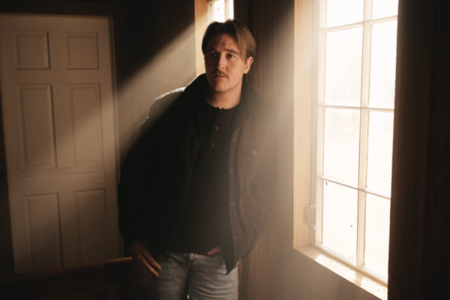 A man is standing in front of a window in a dark room.