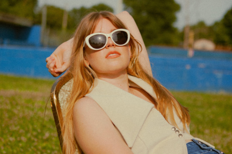 A woman wearing sunglasses is sitting in a chair in the grass.
