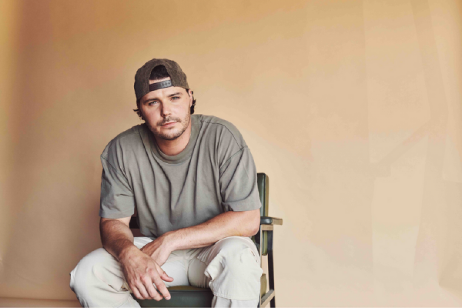 A man is sitting in a chair wearing a hat and a t-shirt.
