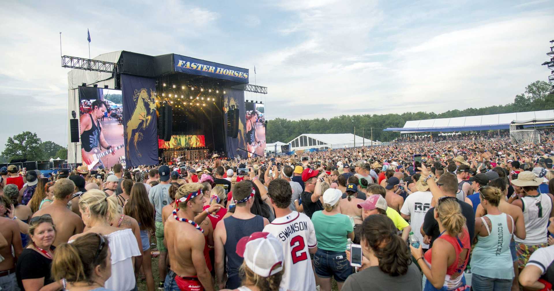A crowd of people are standing in front of a stage at a concert.
