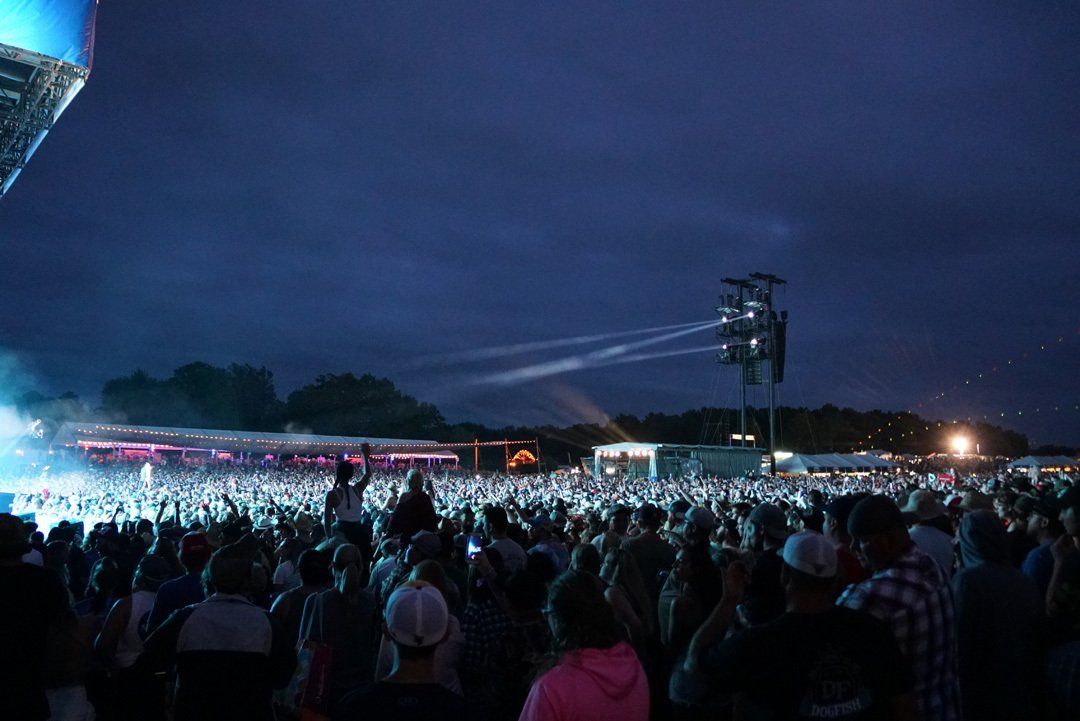 A large crowd of people are watching a concert at night