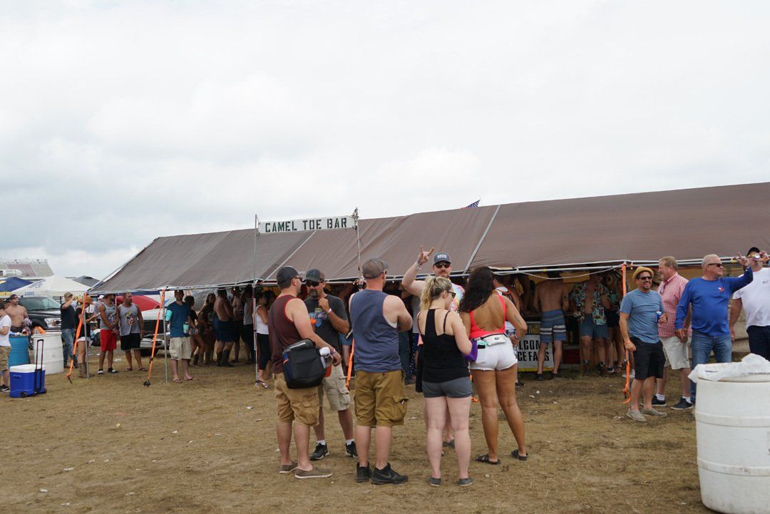 A group of people are standing in a field under a tent.