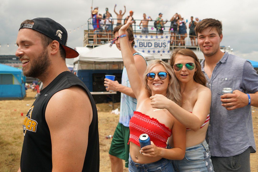 A group of people are standing in front of a bud bus.
