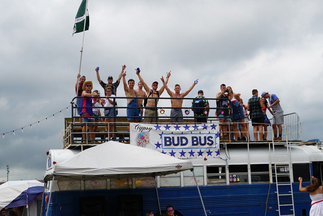 A group of people standing on top of a bud bus