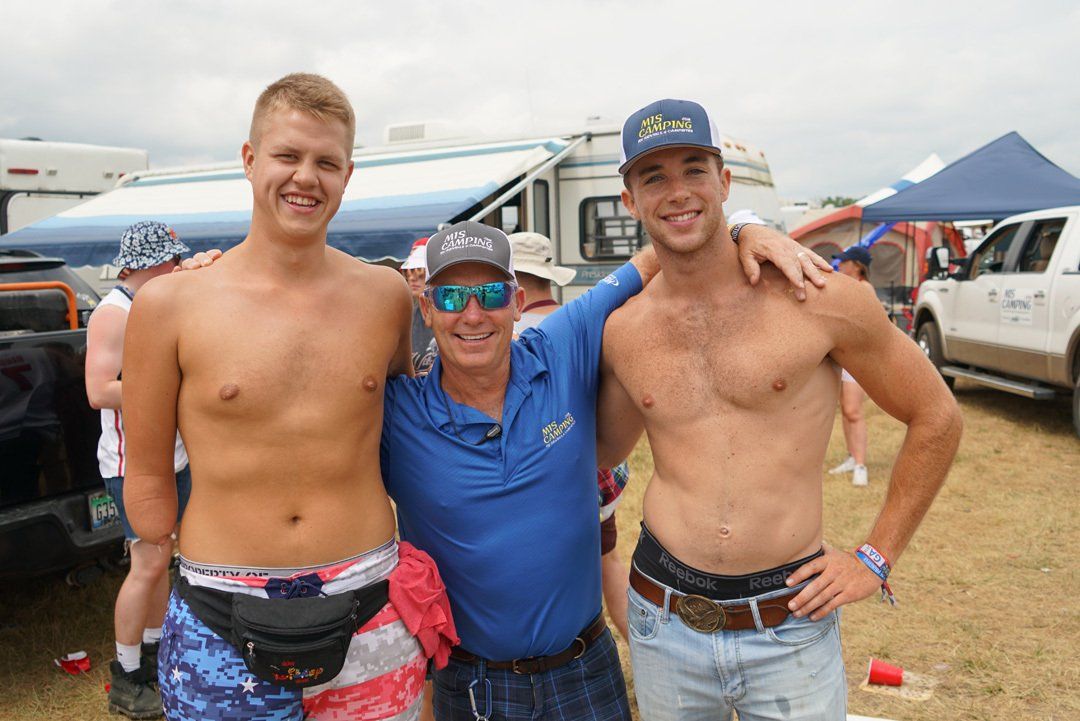 Three shirtless men are posing for a picture in a field.  Andy Winnie