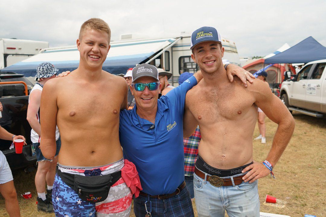 Three shirtless men are posing for a picture in a field.  Andy Winnie with 2 workers
