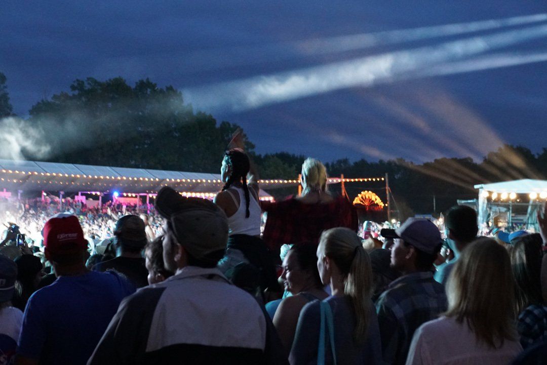 A crowd of people are watching a concert at night