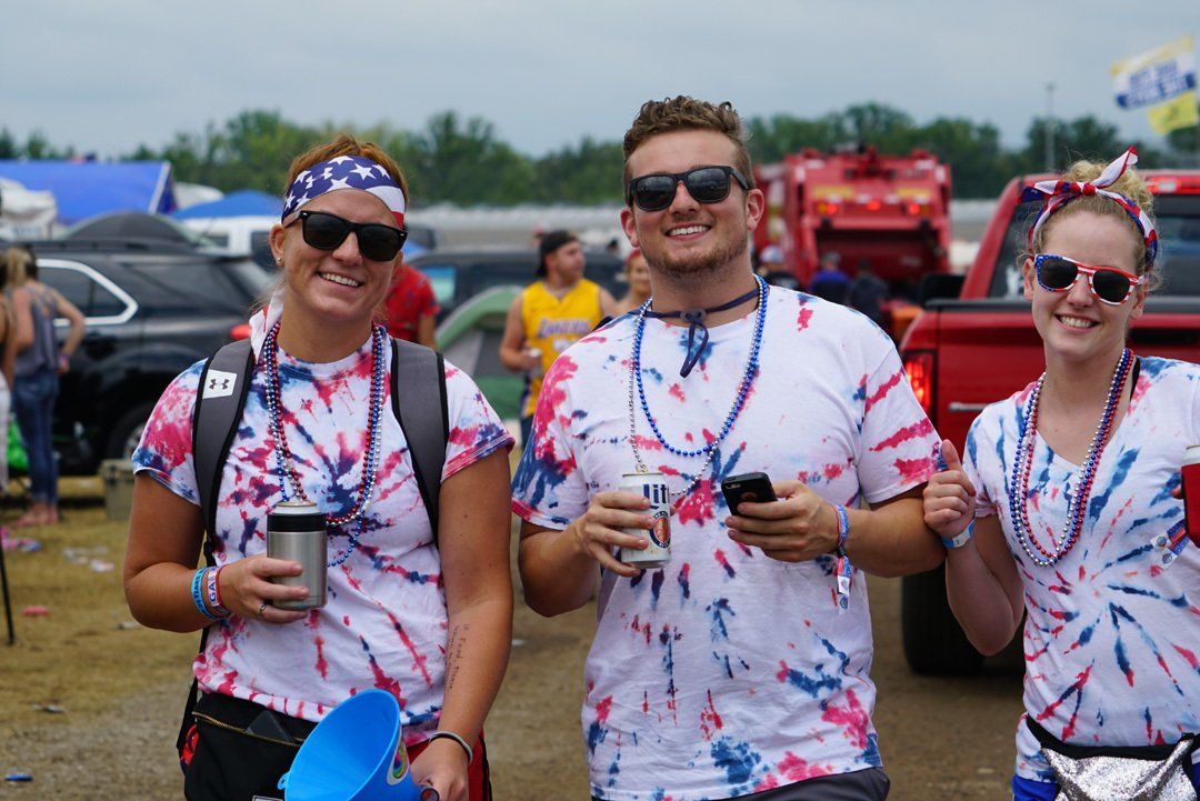 A group of people wearing tie dye shirts are standing next to each other.