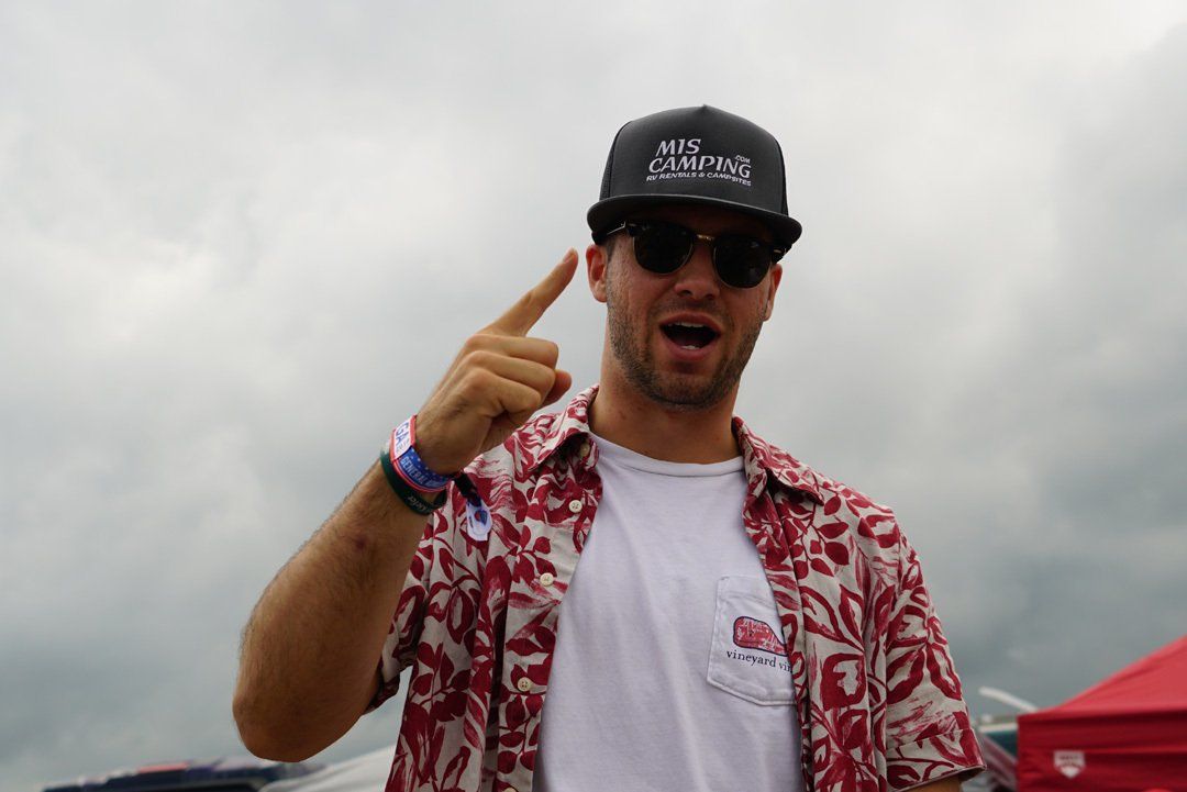 A man wearing a hat and sunglasses is pointing at something.  Nate Winnie