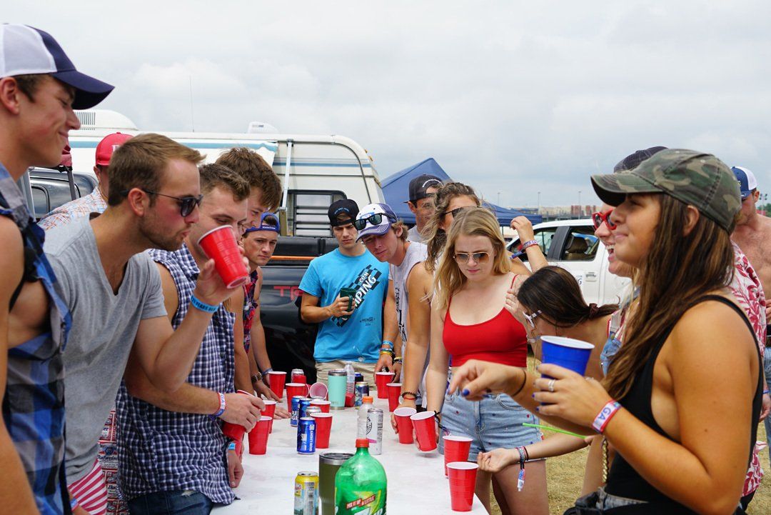 A group of people are standing around a table drinking beer.
