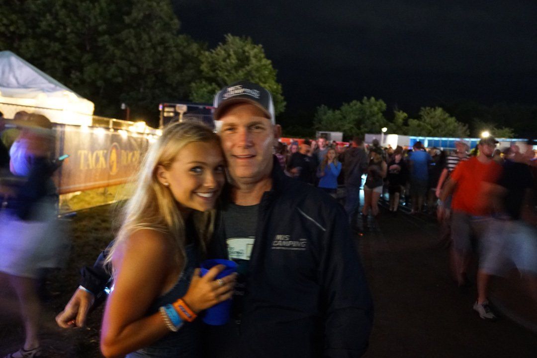 A man and a woman are posing for a picture at a concert.