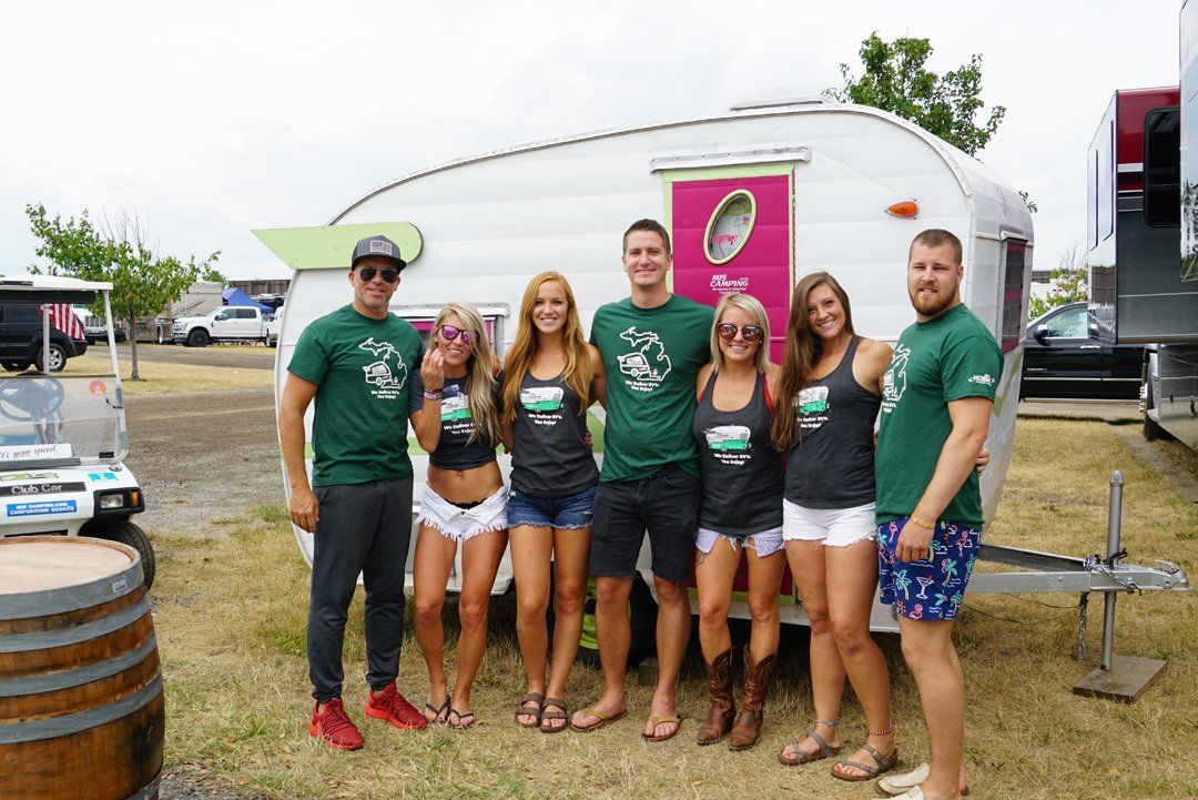 A group of people are posing for a picture in front of a trailer.