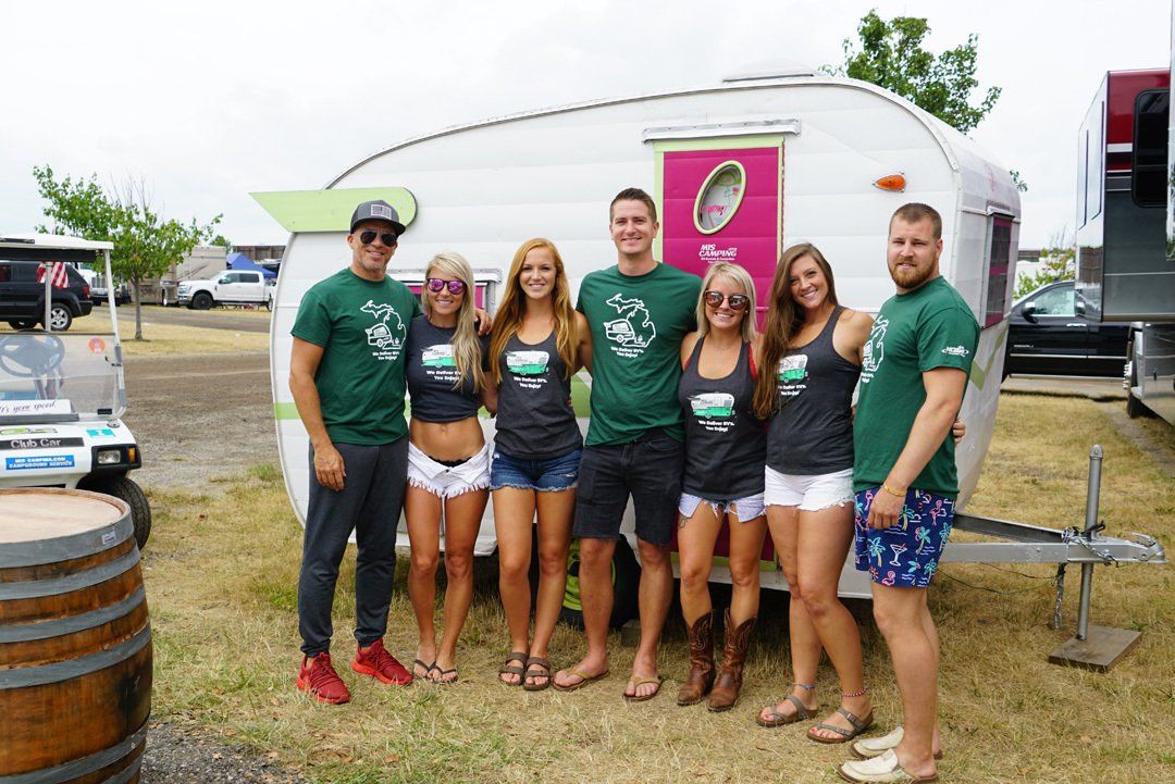 A group of people are posing for a picture in front of a trailer.