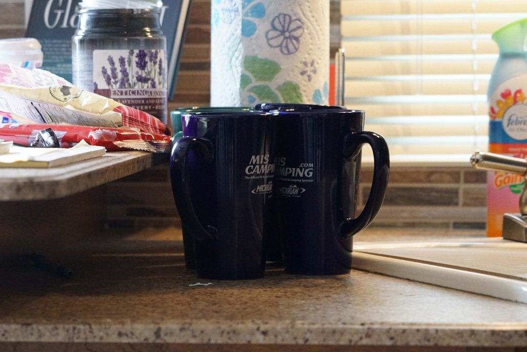 Two blue coffee mugs are sitting on a kitchen counter.