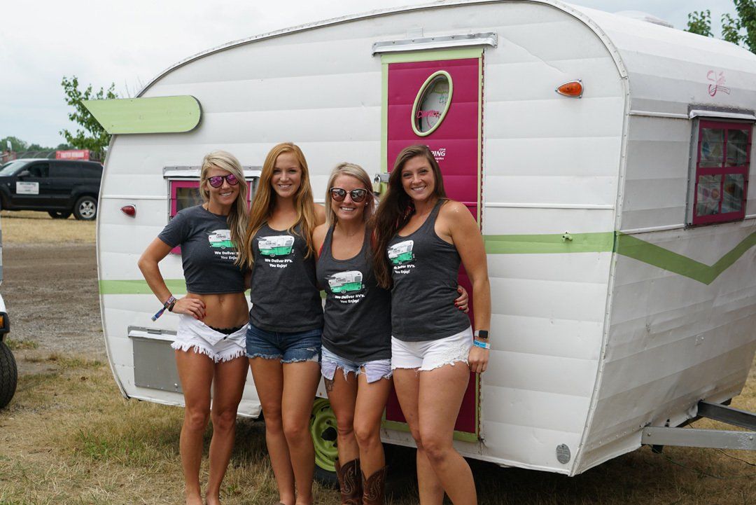 Four women are posing for a picture in front of a trailer.