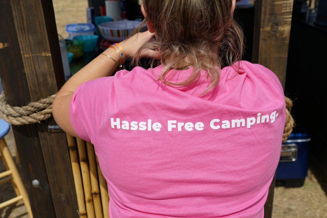 A woman wearing a pink shirt that says hassle free camping