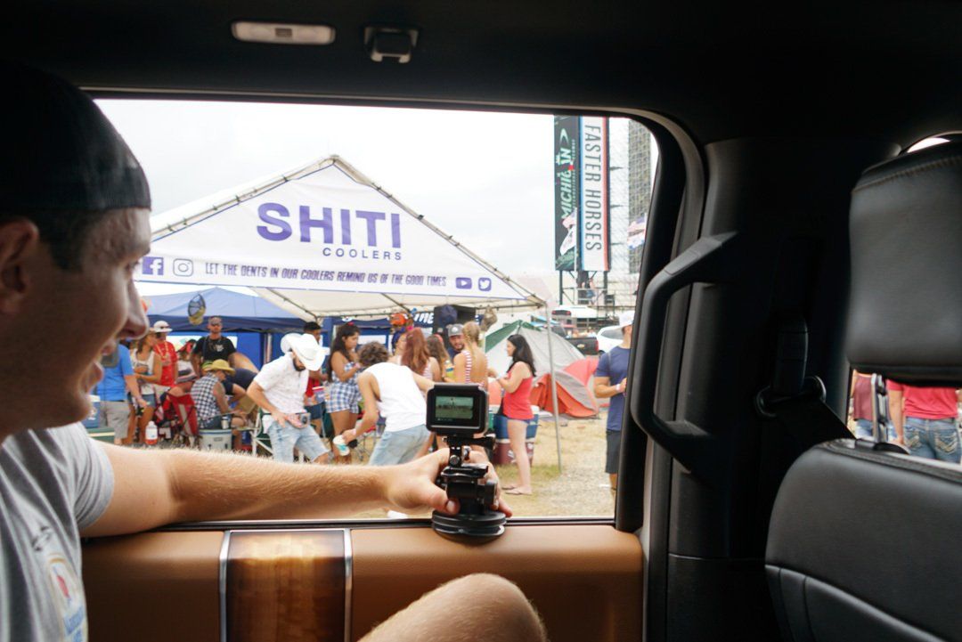 A man is sitting in the back seat of a car holding a camera.