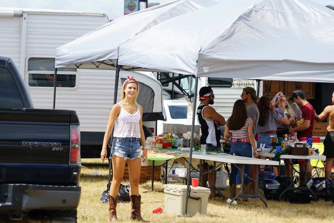 A woman is standing in front of a truck in a field.