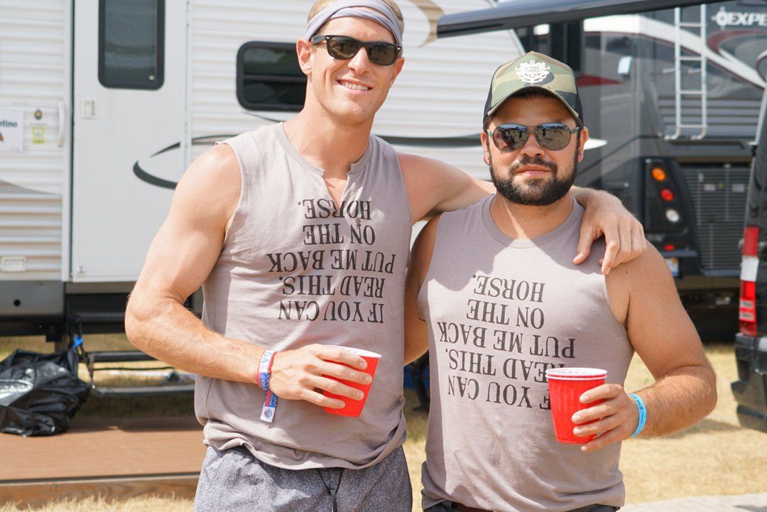 Two men are posing for a picture in front of a trailer.