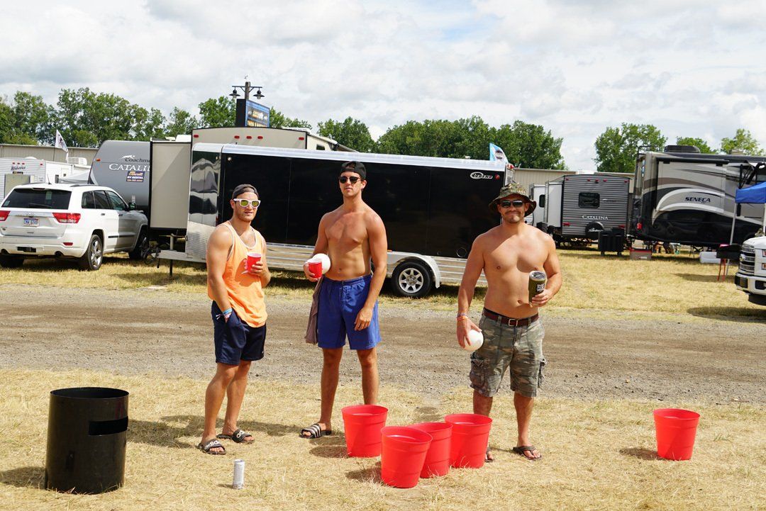 Three men are standing in a field with red buckets.