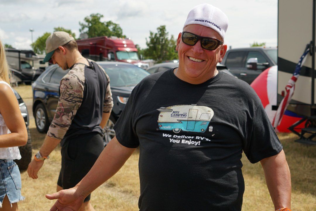 A man wearing a black t-shirt with a picture of a camper on it is smiling.