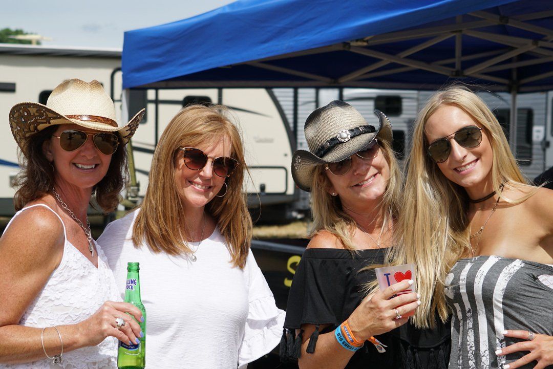 A group of women are posing for a picture under a blue tent.