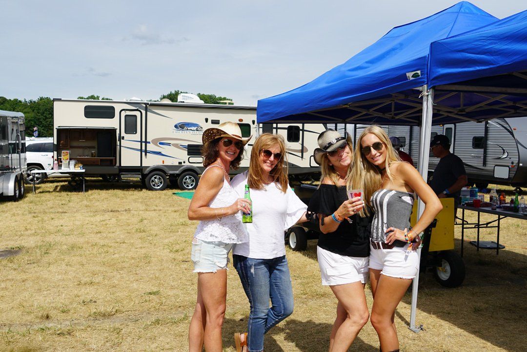 A group of women are standing under a blue tent in a field.