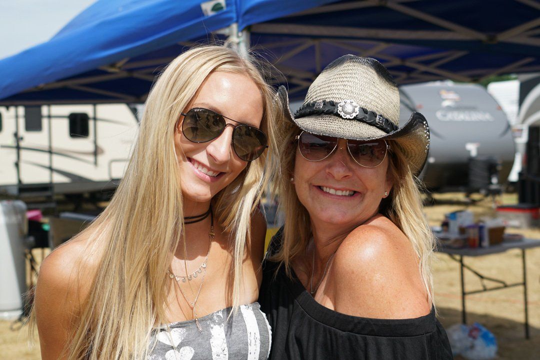 Two women wearing sunglasses and hats are posing for a picture.