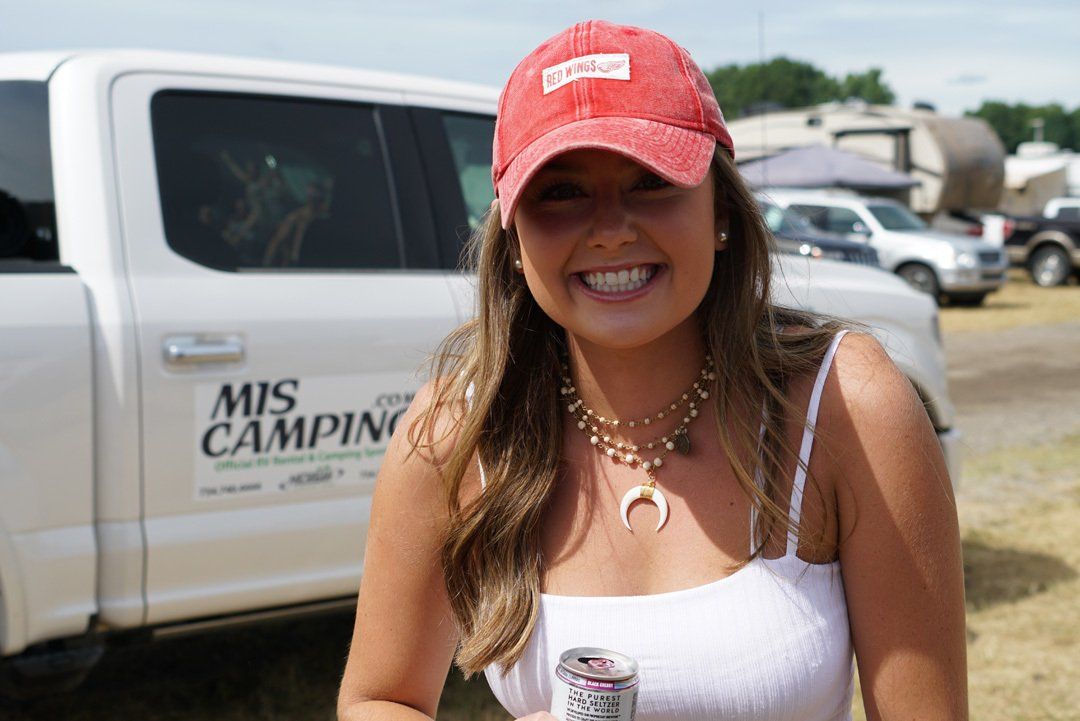 A woman wearing a red hat is standing in front of a white truck.