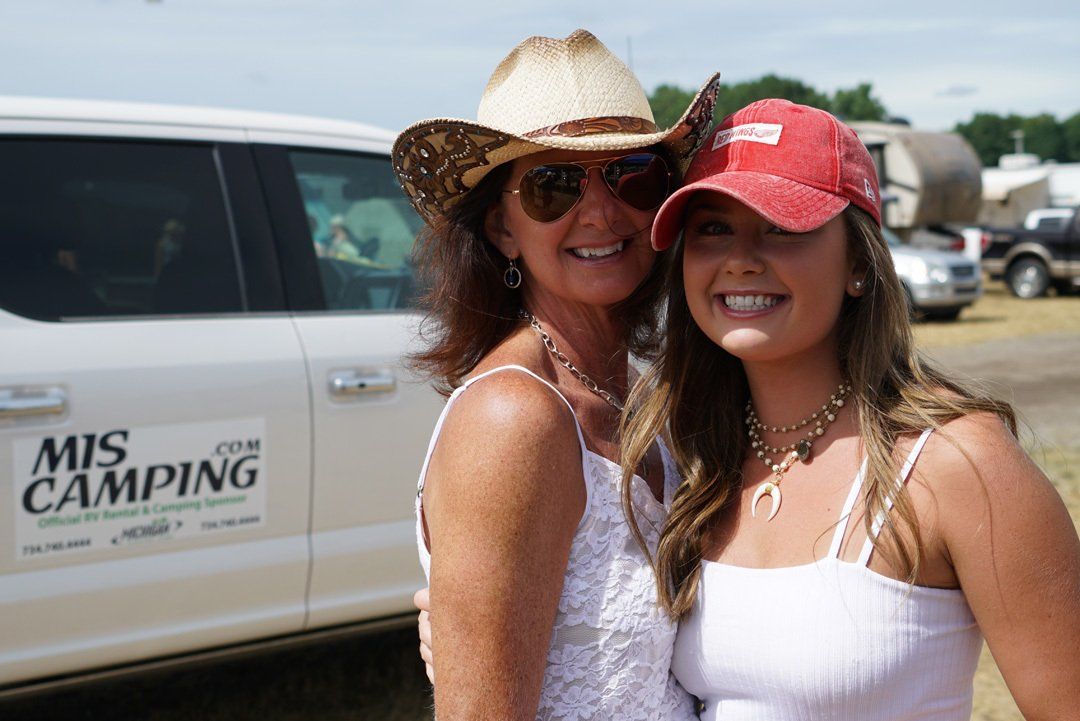 Two women are posing for a picture in front of a mis camping truck