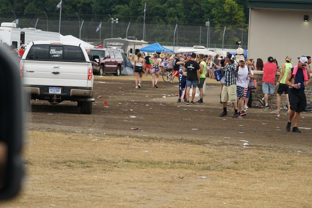 A group of people are gathered in a muddy field with a white truck parked in the background