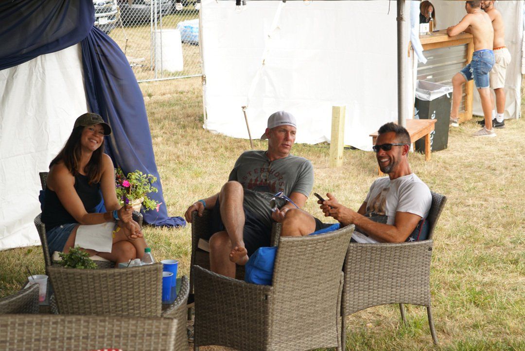 A group of people are sitting in wicker chairs in a field.