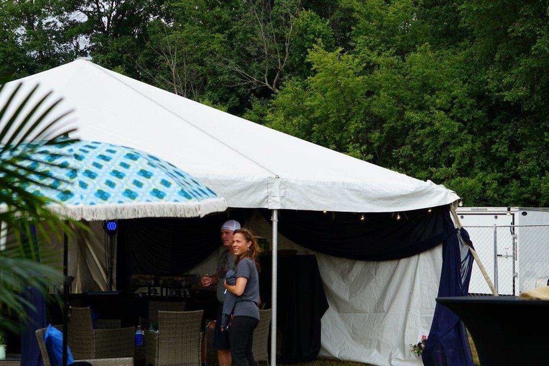 A man and a woman are standing under a white tent